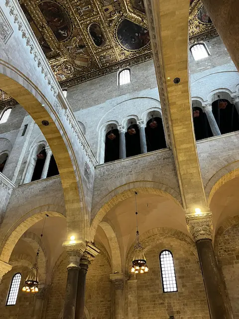 Interior of Basilica di San Nicola in Bari with Romanesque arches and ornate Baroque ceiling
