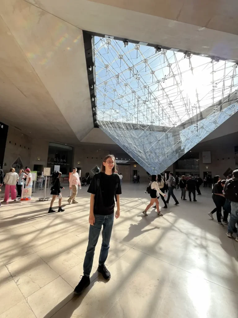 Donny at the Louvre Museum in Paris Donny, the creator of Artsy Trips, standing under the Louvre Pyramid in Paris, France